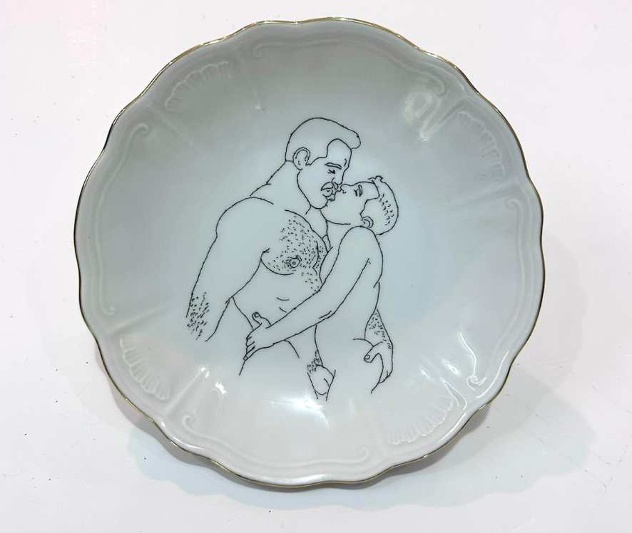 Omri Danino Porcelain Plate engraved with a drawing of nude male models: older hairy man and younger man kissing, in black engraving on white plate with golden rim