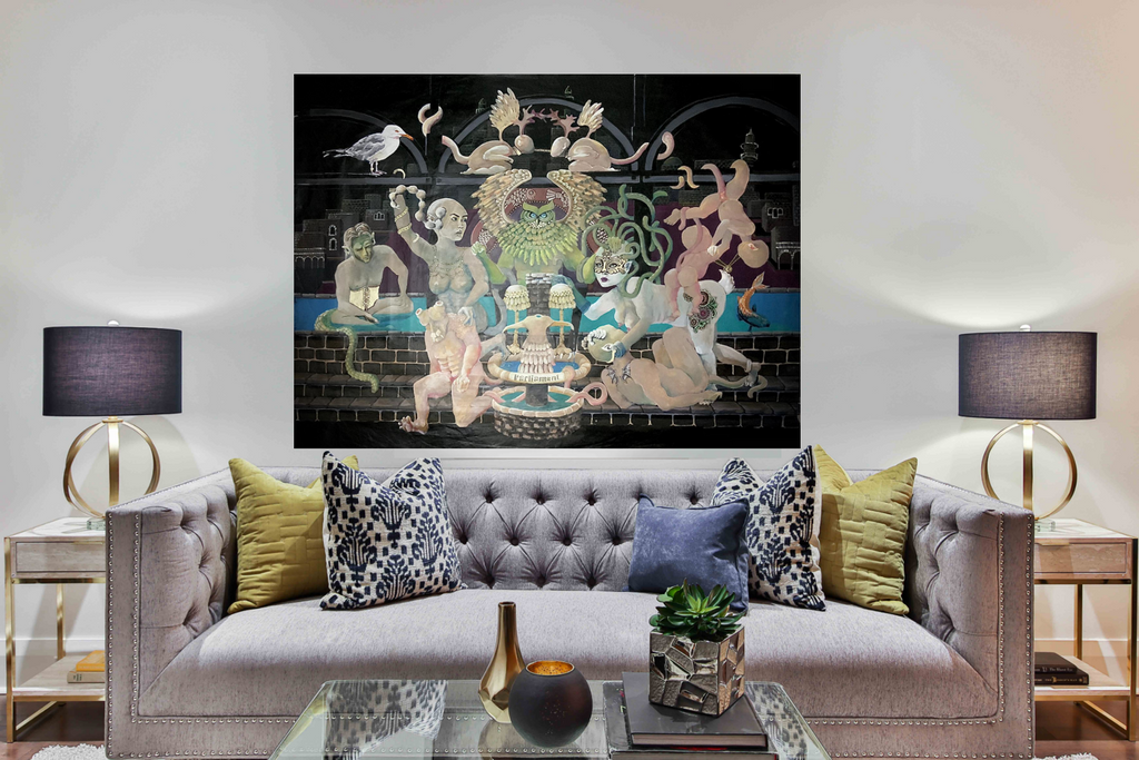 Hanging illustration - an oil painting by Daphne Shani - a surrealist depiction of characters that are part beast part human around a fountain. A mother breastfeeding a baby and there are flying naked toddlers. along with a seagull, an owl and fish, on the background is the city Tiberias with the iconic black basalt cottages - hung in a livingroom